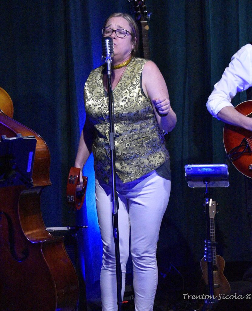 Jennifer Wells singing in a gold vest on St. Patrick's Day