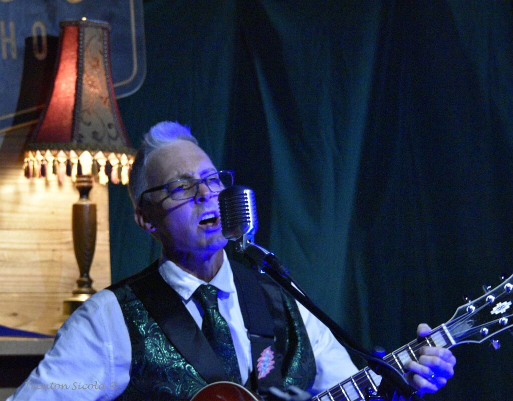 Matt Donald close up sings and plays guitar at Waller's Coffee shop with Gin Joint Rascals