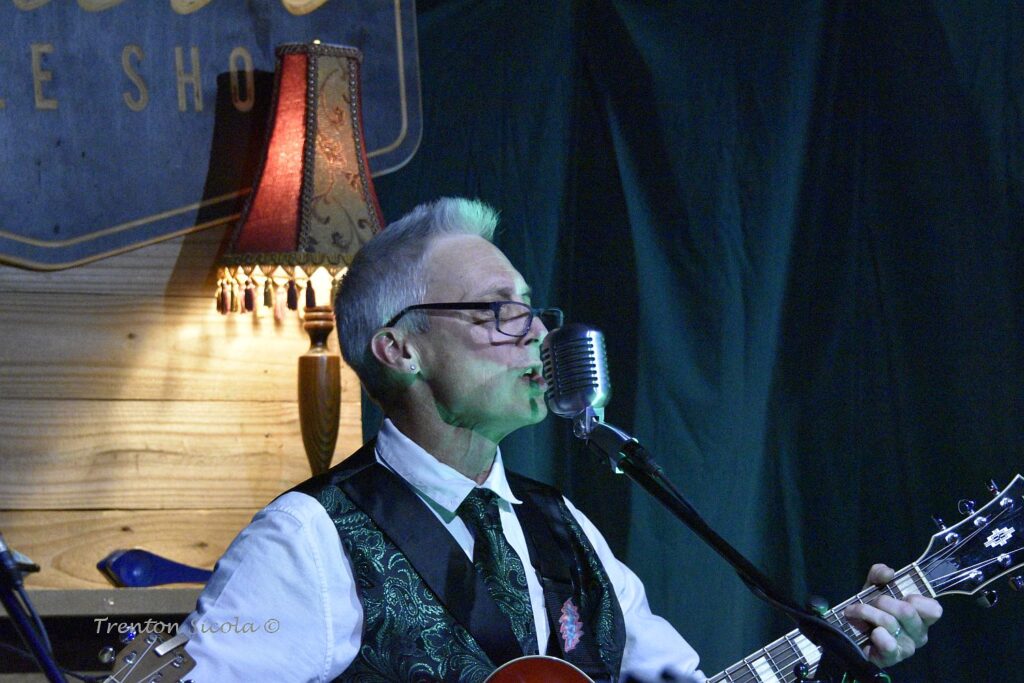 Matt Donald close up sings and plays guitar at Waller's Coffee shop with Gin Joint Rascals