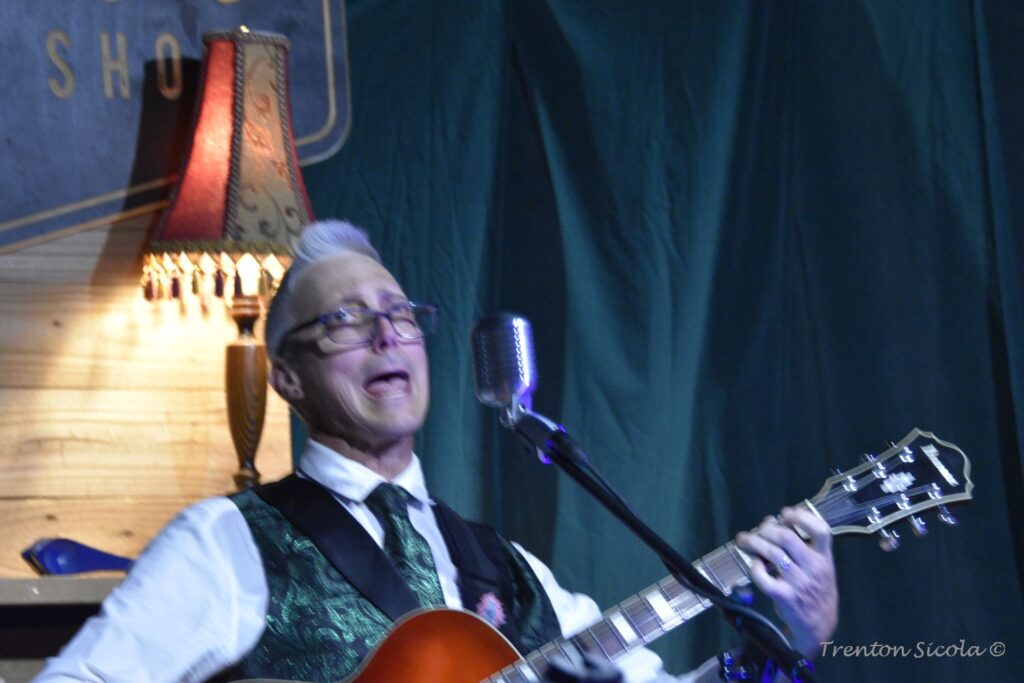 Matt Donald close up sings and plays guitar at Waller's Coffee shop with Gin Joint Rascals